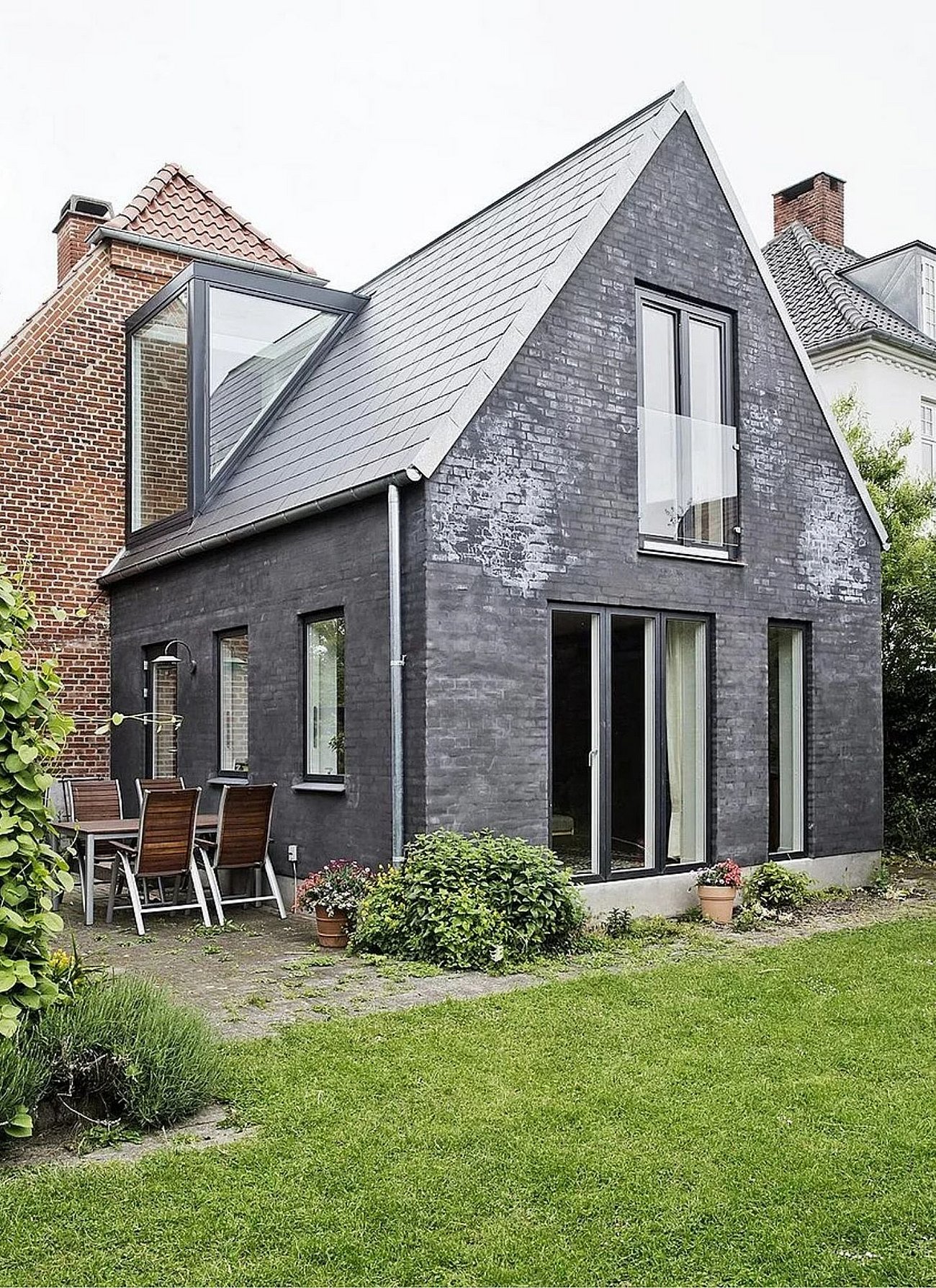 Sort muret tilbygning med glaskvist i kontrast til klassisk murermestervilla
