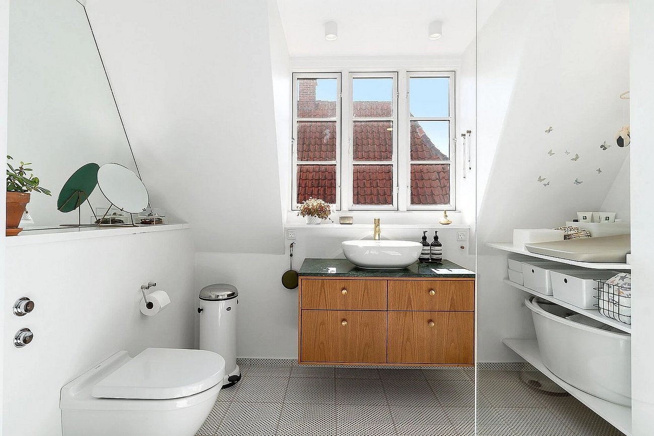 Lyst badeværelse med skrå vægge og kvist i murermestervilla