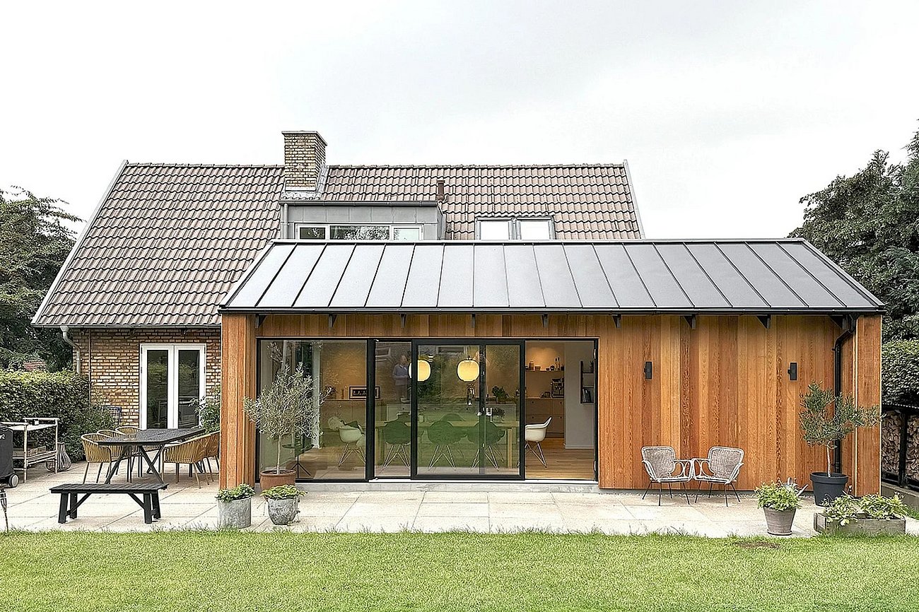 Enkel tilbygning med gyldne træfacader til murermestervilla fra 50'erne