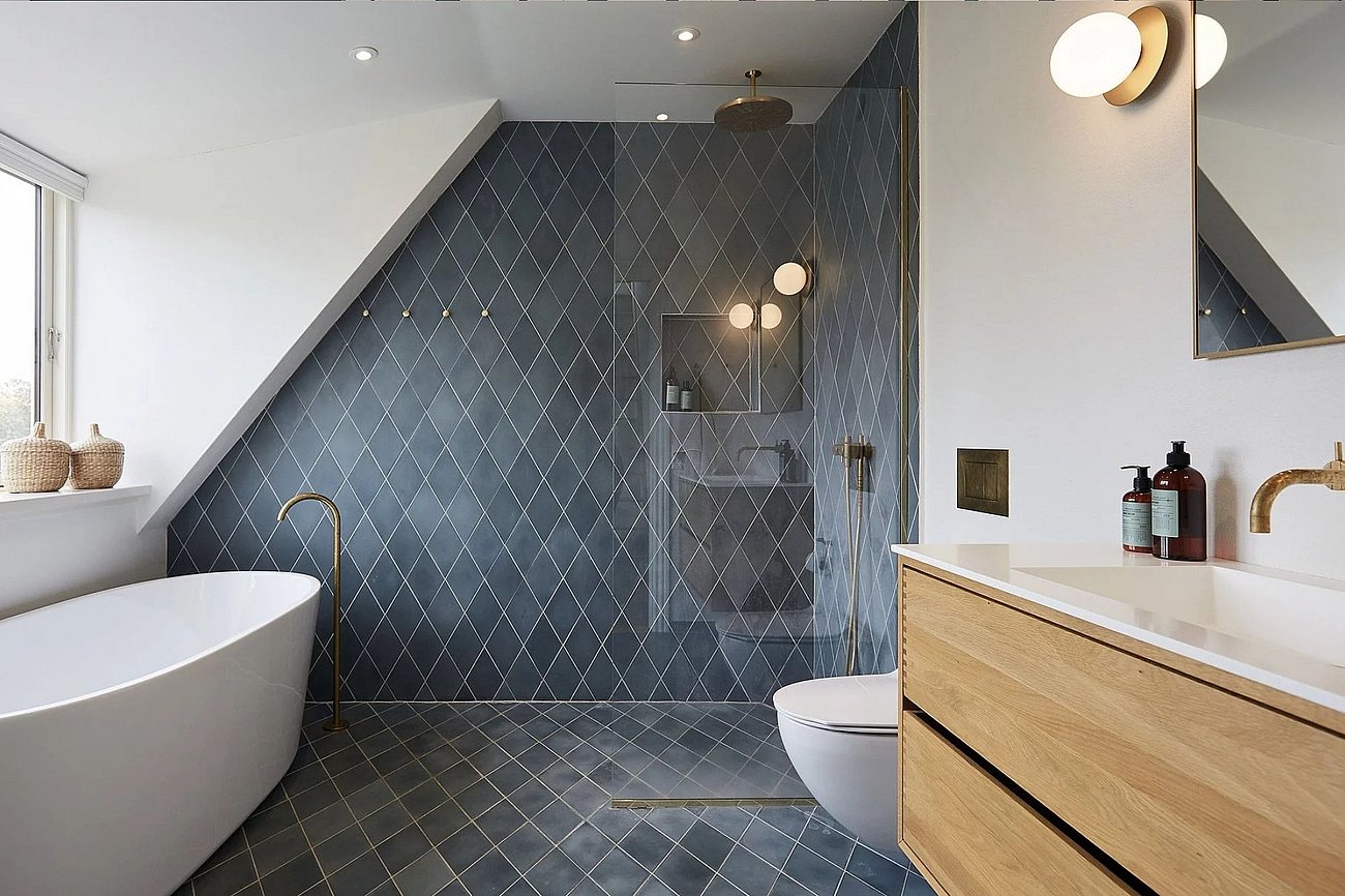 Stort lyst badeværelse med blå rombeformede fliser og armaturer i messing
