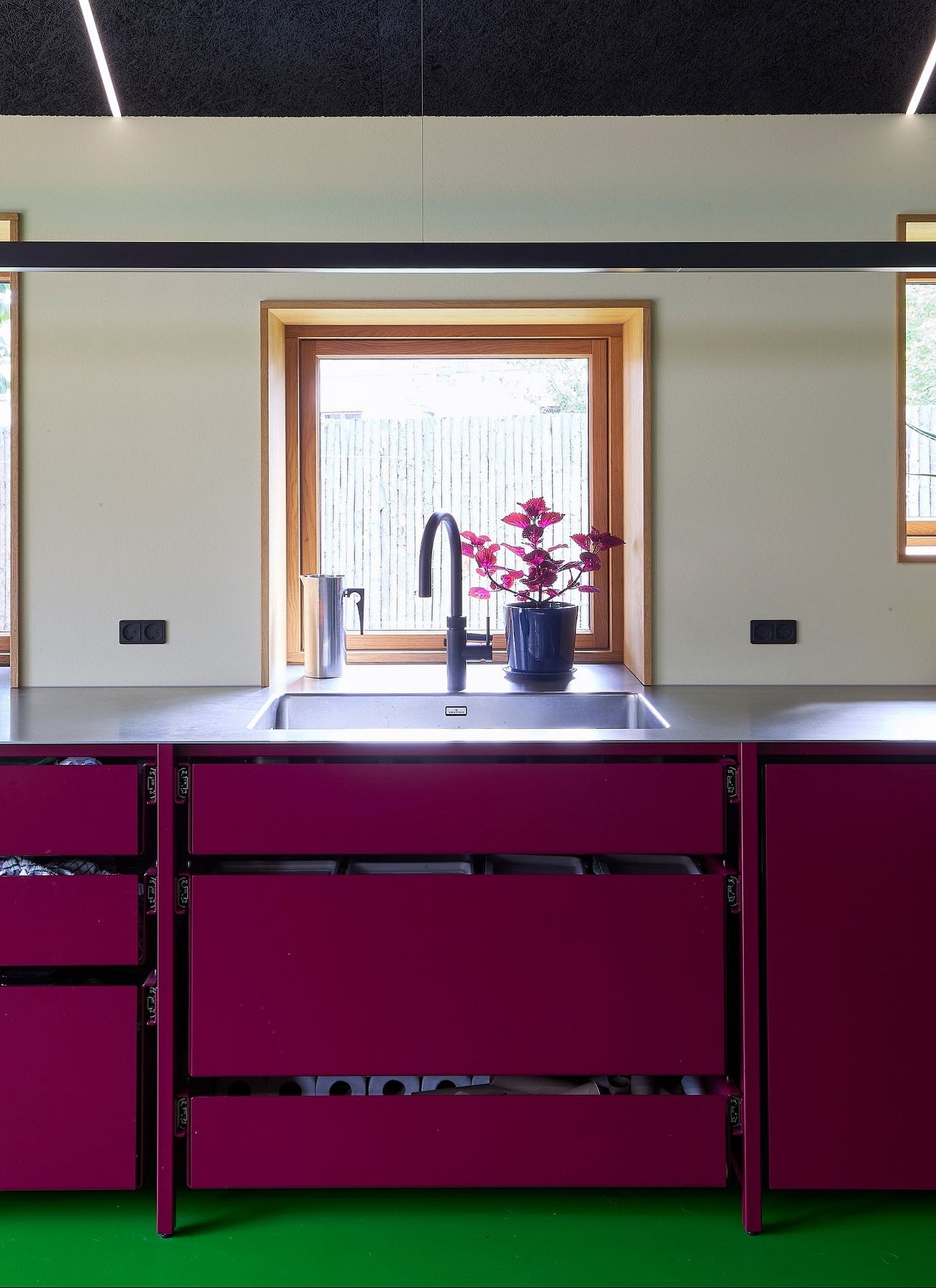 Stålkøkken i bordeaux violette farve med grønt gulv