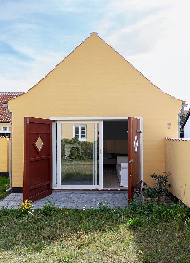 Klassisk gult sommerhus i Skagen med lille stenterrasse