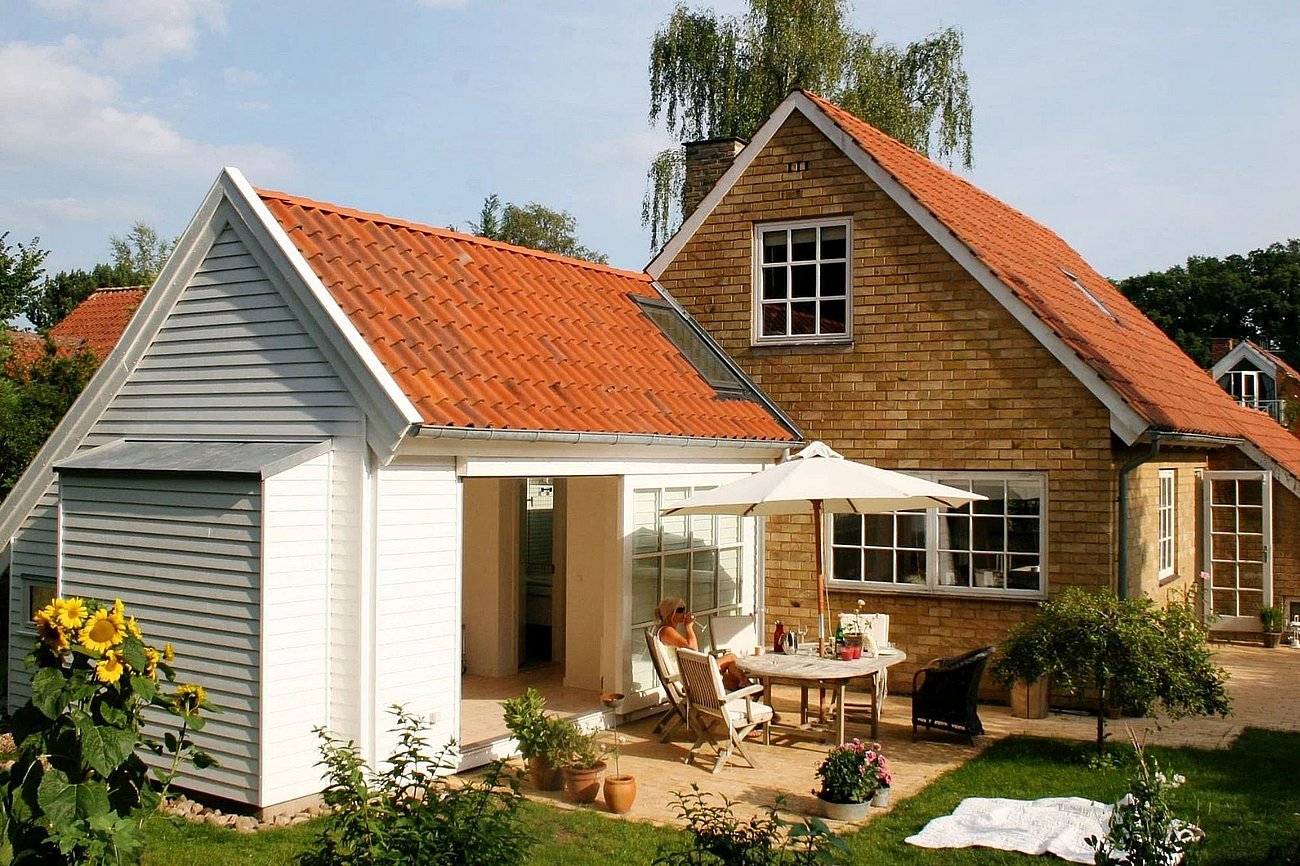 Tilbygning beklædt med hvidmalet træ til murermestervilla fra 50'erne