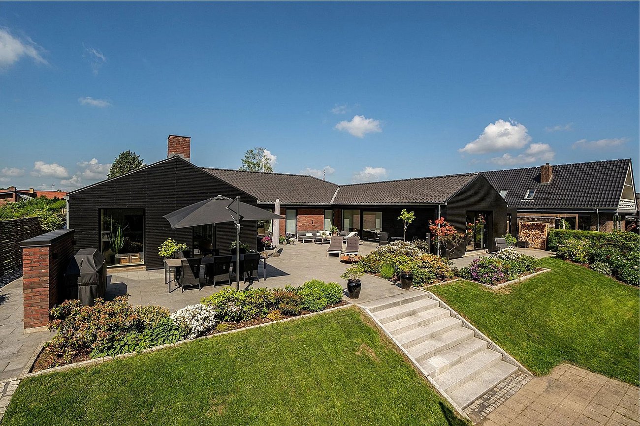 Stor fliseterrasse til 70'er-typehus tilpasset skrånende grund