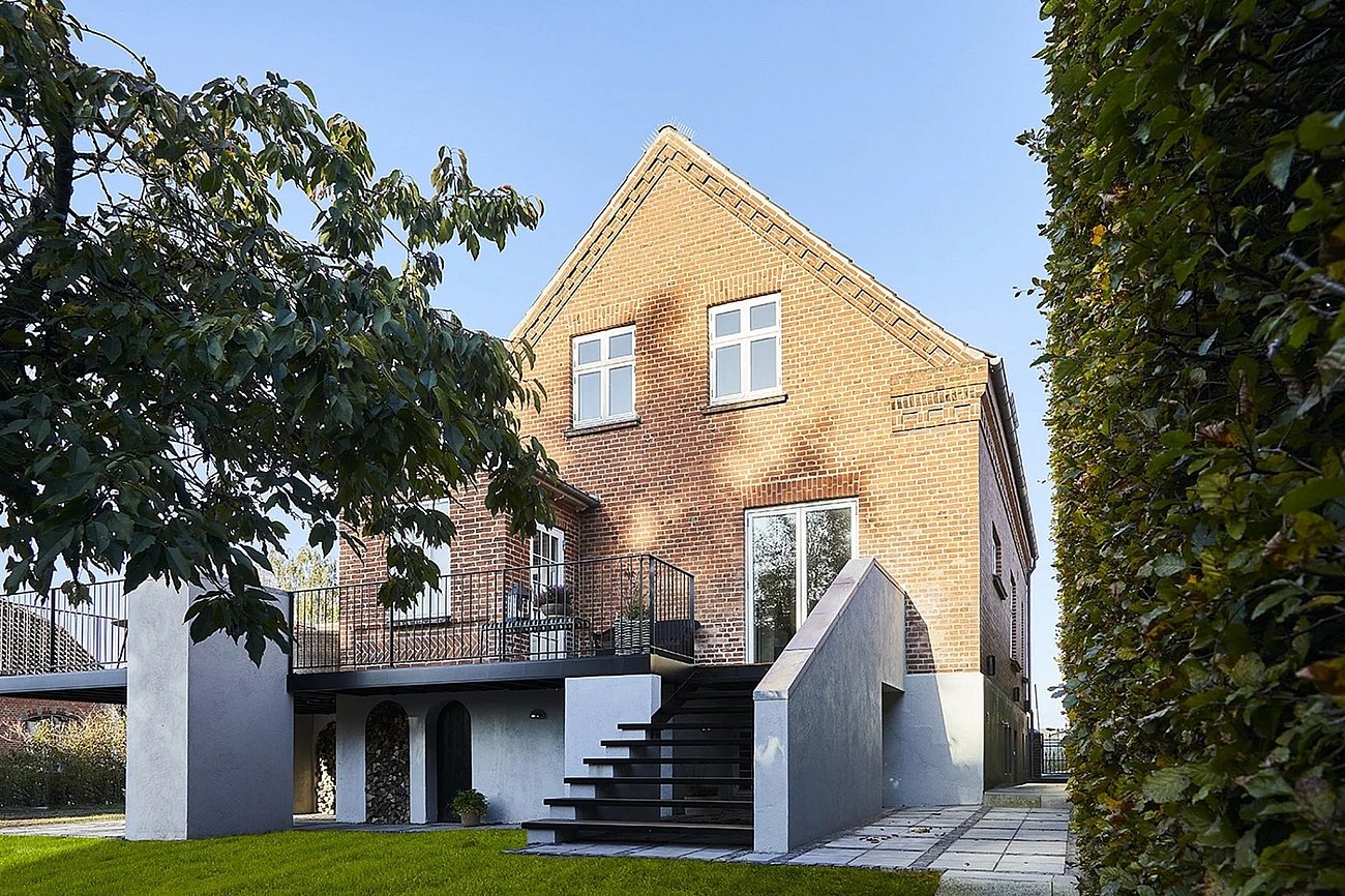 Hævet terrasse til murermestervilla skaber overdækning til terrasse i haveplan