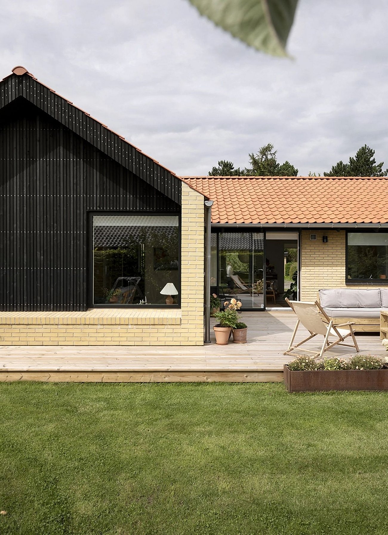 Sort træbeklædt tilbygning med gavl og gennemgående brystning til 60'er villa