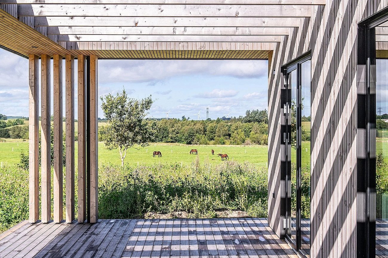 Overdækket terrasse med rene linjer og funktionelt udtryk i nybygget sommerhus af bæredygtige materialer
