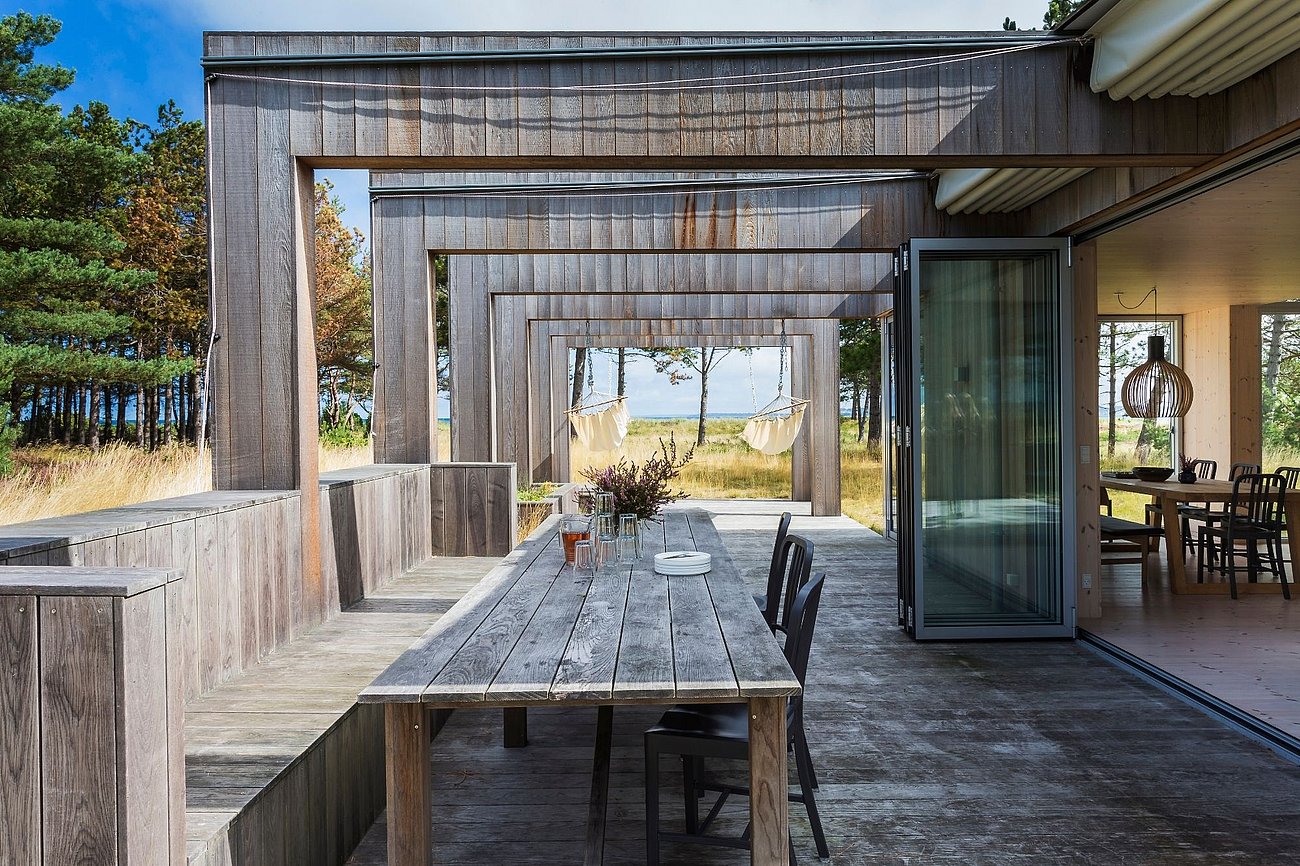 Nordisk træterrasse med overdækning, bordbænke og udekøkken