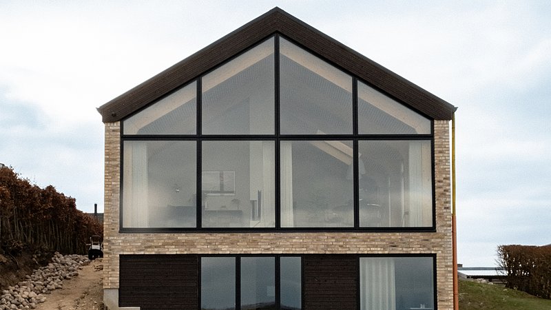 Hvor facaden før ombygningen fremstod indadvendt og lukket, er den nu transformeret til en åben konstruktion, der inviterer naturen helt ind i boligen.